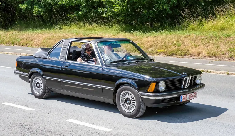 A classic convertible driving along a country road