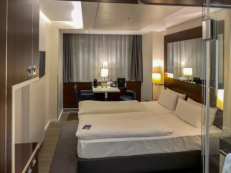 A made-up hotel bedroom with a large bed and bedside lamps